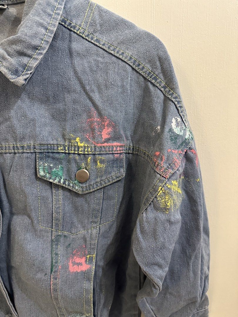 Mila Distressed Denim Jacket with Paint Splatter and Graffiti (Category: Coats, Jackets and Outerwear) located in Pasig City. Submitted by gwi0mi (Listing ID 1447874143, Image 3). Description: Brand: Mila Size: L Length: 22.9in Width: 22.5in Sleeve length: 28.5in Style: Denim Jacket Features: Distressed hem and cuffs Design: Colorful paint splatters all over Back Detail: Graffiti-style writing Condition: 10/10 No flaws Unique, great for layering.