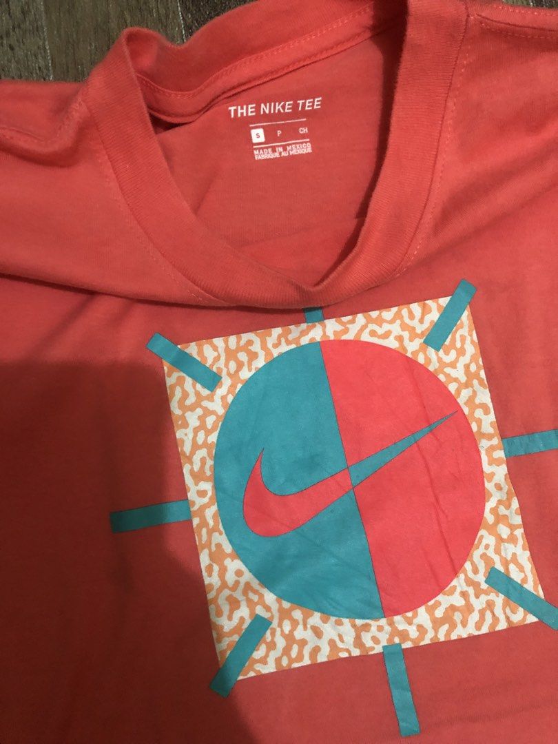 Nike T-Shirt Coral Graphic Tee (Category: Activewear) located in Manila. Submitted by tonettesells (Listing ID 1447833231, Image 2). Description: - Color: Coral - Brand: Nike - Size: L - Design: Unique circular graphic with teal and red sections, plus a Nike swoosh - Origin: Made in Mexico - Best for: Casual wear.