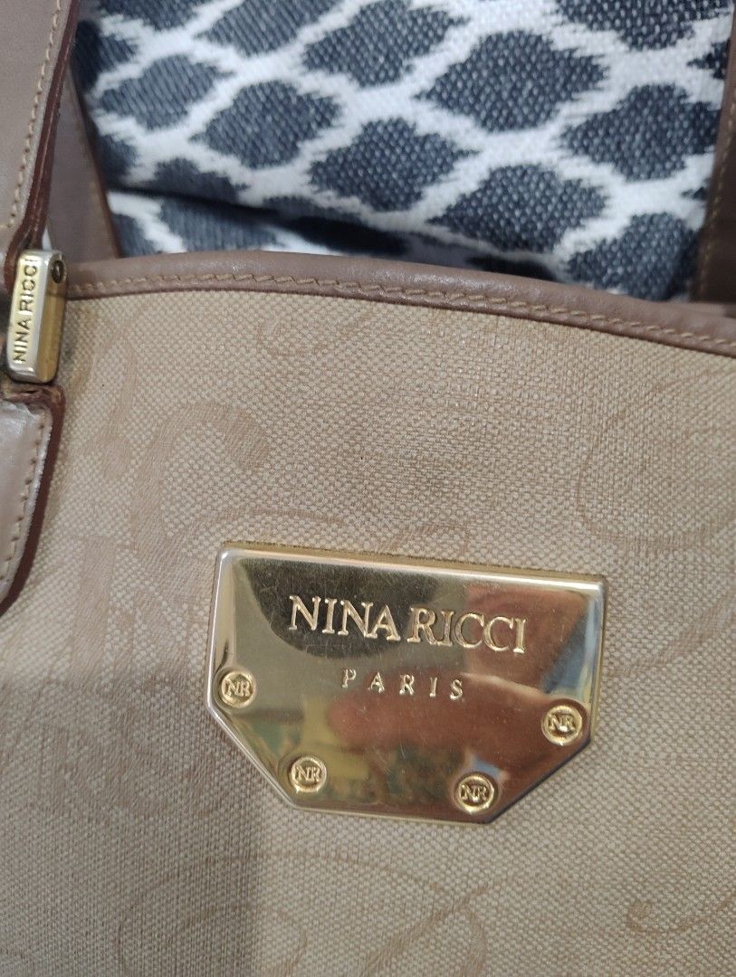 Nina Ricci Tote Bag Classic (Category: Shoulder Bags) located in Manila. Submitted by dcsago (Listing ID 1447727429, Image 3). Description: Brand: Nina Ricci Paris Style: Large shoulder tote Material: Beige coated canvas/jacquard with an all-over "NR" monogram pattern Trim: Brown leather or leather-look trim and shoulder straps Hardware: Gold-tone front plaque engraved "NINA RICCI PARIS" with NR-logo screws A vintage or early-2000s licensed Nina 