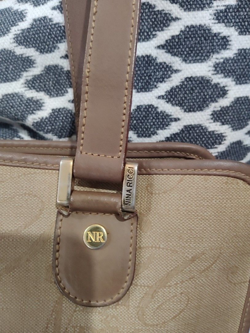 Nina Ricci Tote Bag Classic (Category: Shoulder Bags) located in Manila. Submitted by dcsago (Listing ID 1447727429, Image 2). Description: Brand: Nina Ricci Paris Style: Large shoulder tote Material: Beige coated canvas/jacquard with an all-over "NR" monogram pattern Trim: Brown leather or leather-look trim and shoulder straps Hardware: Gold-tone front plaque engraved "NINA RICCI PARIS" with NR-logo screws A vintage or early-2000s licensed Nina 