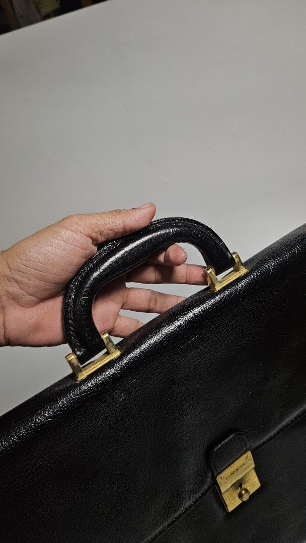 Vintage Lancel Black Leather Briefcase (Category: Luxury Bags & Wallets) located in Alfonso. Submitted by jbcamet (Listing ID 1447813021, Image 3). Description: - Classic black leather briefcase - Secure gold clasp closure - Sturdy top handle - Visible Lancel logo on hardware - Ample interior space for documents and laptop - Ideal for work or business trips.