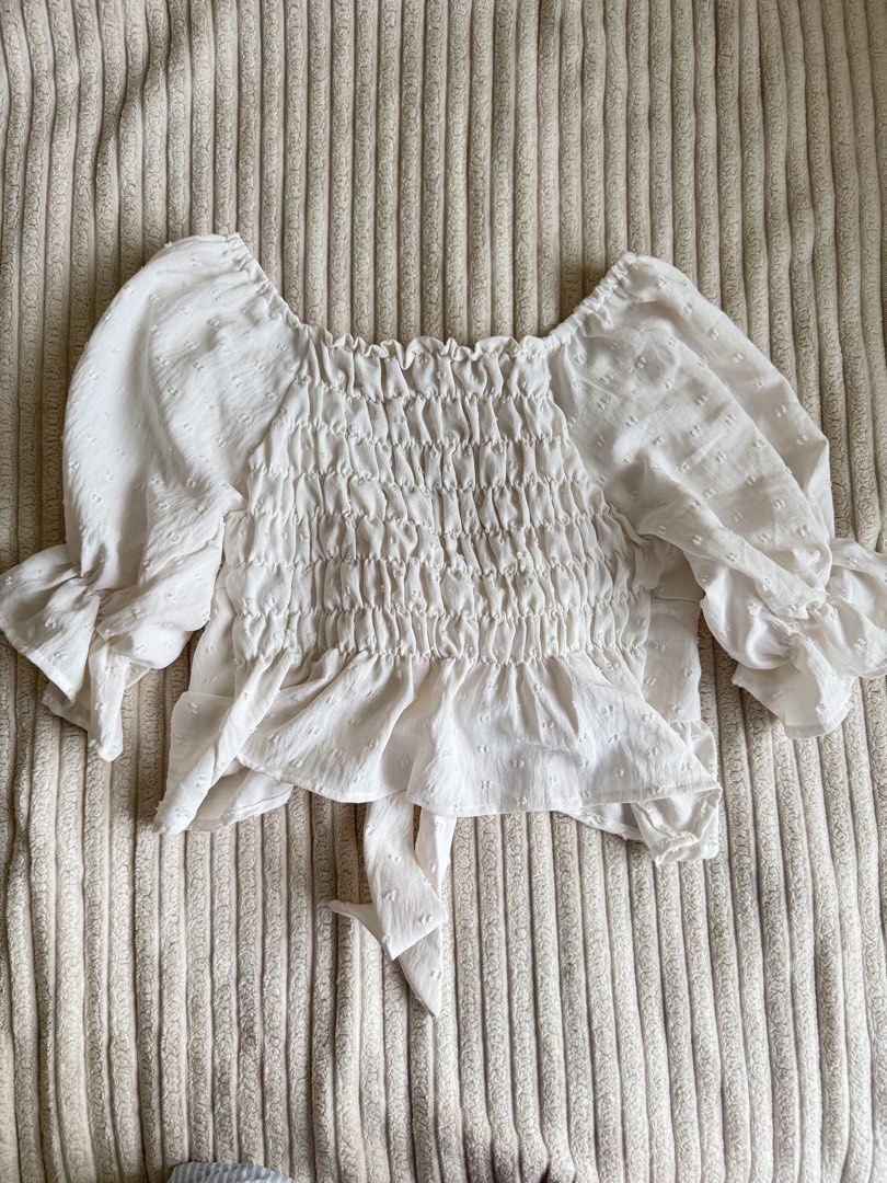 White Smocked Peplum Top with Tie Front (Category: Sleeveless) located in Taguig. Submitted by _anythingpreloved (Listing ID 1447749087, Image 2). Description: - Adorable white peplum top - Features a smocked bodice for a comfortable fit - Stylish puff sleeves with ruffled cuffs - Cute front tie detail - Subtle textured fabric pattern - Versatile: pairs perfectly with jeans or skirts.