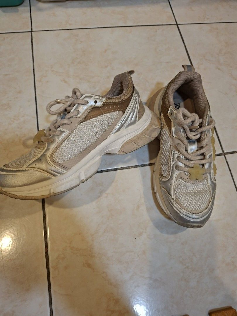 ZARA Kids Sneakers Size 33 (Category: Babies & Kids Fashion) located in Pasig City. Submitted by aubshop (Listing ID 1447757848, Image 2). Description: - ZARA kids sneakers - Beige and silver colorway - Mesh and synthetic material - Lace-up closure with flower detail on laces - Soles show some wear - Perfect for everyday wear.