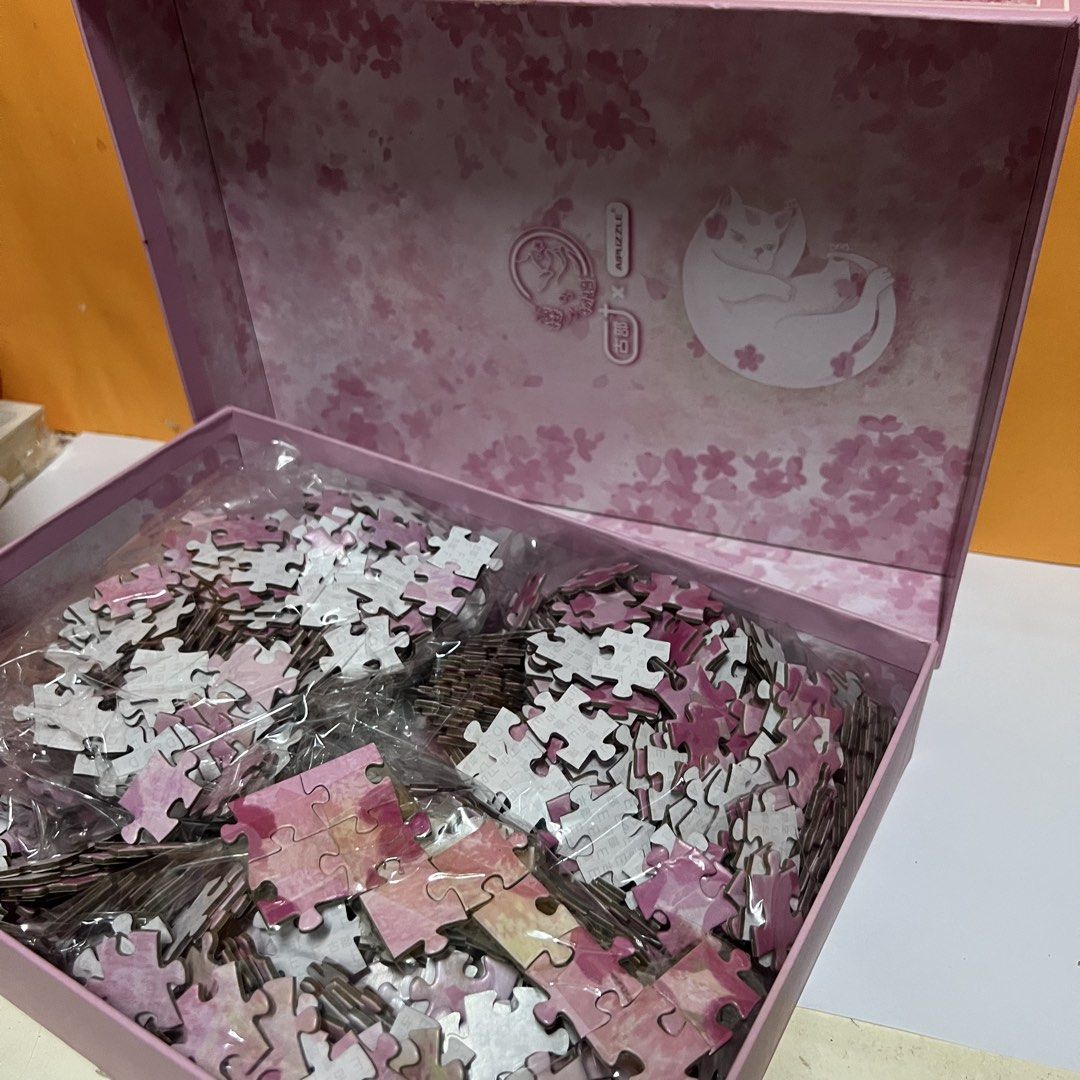 1000 Piece Jigsaw Puzzle - Cat & Cherry Blossoms (Category: Art & Prints) located in Imus. Submitted by vansteph_080923 (Listing ID 1447954994, Image 3). Description: - 1000 piece jigsaw puzzle - Adorable sleeping cat design surrounded by cherry blossoms - Pink and floral themed box and pieces - Ideal for a relaxing and calming activity - Completed puzzle size: 530mm x 750mm - Comes with a poster guide for assistance - Has a few missing/damaged p