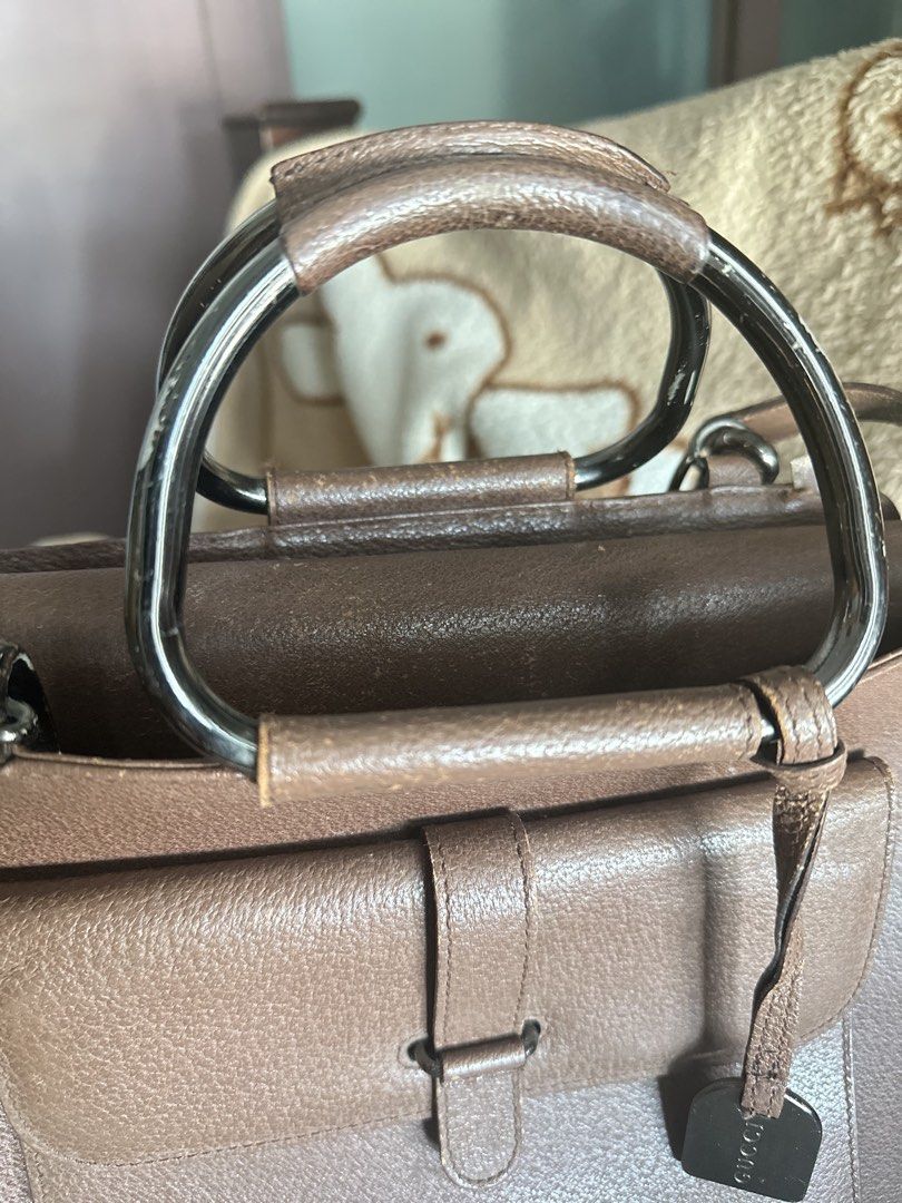 Gucci Brown Leather Top Handle Bag (Category: Luxury Bags & Wallets) located in Mandaluyong City. Submitted by TheWeekendProject (Listing ID 1447986527, Image 2). Description: - Authentic brown leather Gucci handbag - Features a front flap pocket with metal snap closure - Unique metal and leather top handle - Interior zippered pocket - Pre-owned vintage condition. - Leather exterior shows minor scuffs and rubbing consistent with age. - Hardware h