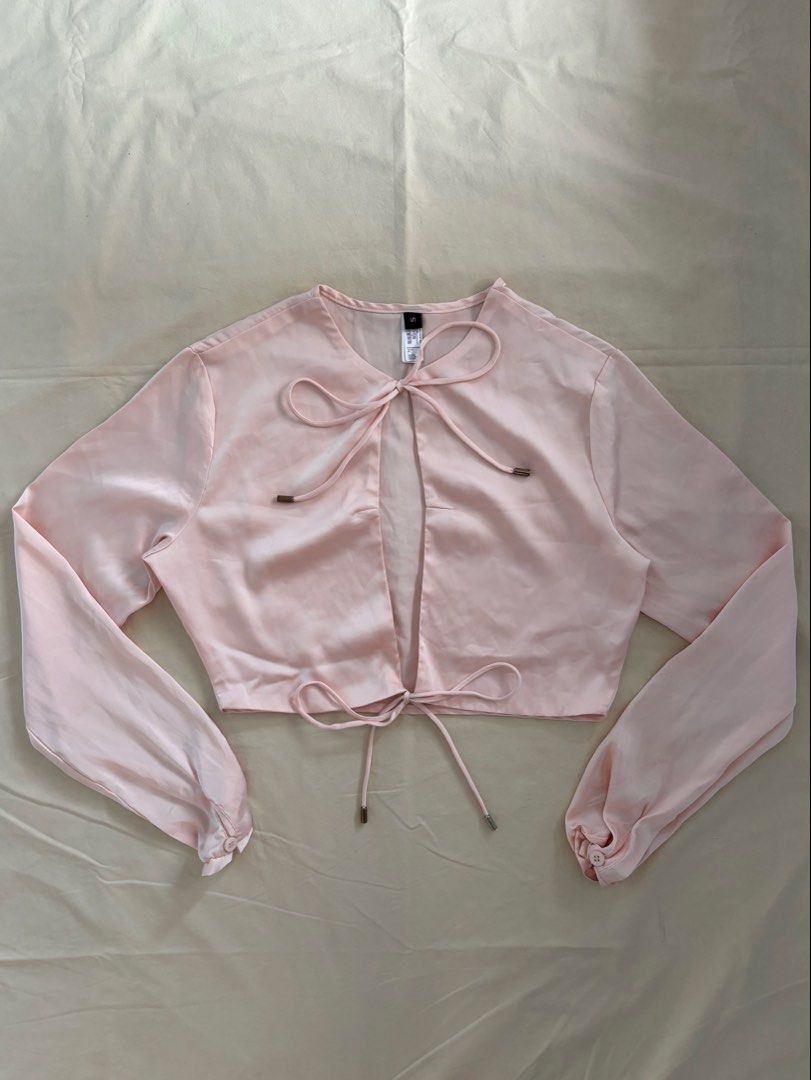 Light Pink Satin Tie-Front Long Sleeve Top (Category: Longsleeves) located in Malabon City. Submitted by ellaeiry (Listing ID 1447981876, Image 1). Description: Size: XS-S [S on Tag] flat lay measurements: w: 17” in. l: 14” in. Brand: Amoricon Apeioar Condition: No flaws Price: PHP 179 - color may vary due to lighting - as a second-hand garment, it may have details that went unnoticed - please don’t hesitate to message me for any inquiries, thank