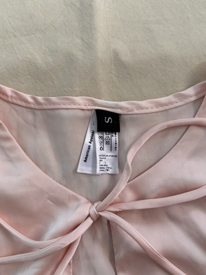 Light Pink Satin Tie-Front Long Sleeve Top (Category: Longsleeves) located in Malabon City. Submitted by ellaeiry (Listing ID 1447981876, Image 3). Description: Size: XS-S [S on Tag] flat lay measurements: w: 17” in. l: 14” in. Brand: Amoricon Apeioar Condition: No flaws Price: PHP 179 - color may vary due to lighting - as a second-hand garment, it may have details that went unnoticed - please don’t hesitate to message me for any inquiries, thank