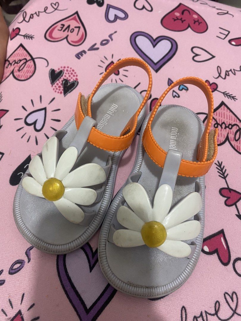 Mini Melissa Daisy Sandals Orange Grey - US 9 (Category: Babies & Kids Fashion) located in Taguig. Submitted by mumpreloveddd (Listing ID 1448064989, Image 1). Description: - Adorable Mini Melissa sandals for little ones. - Grey base with vibrant orange straps. - Features a cute daisy flower with a gold center. - Easy velcro strap for a secure and adjustable fit. - Ideal for summer adventures and everyday wear..