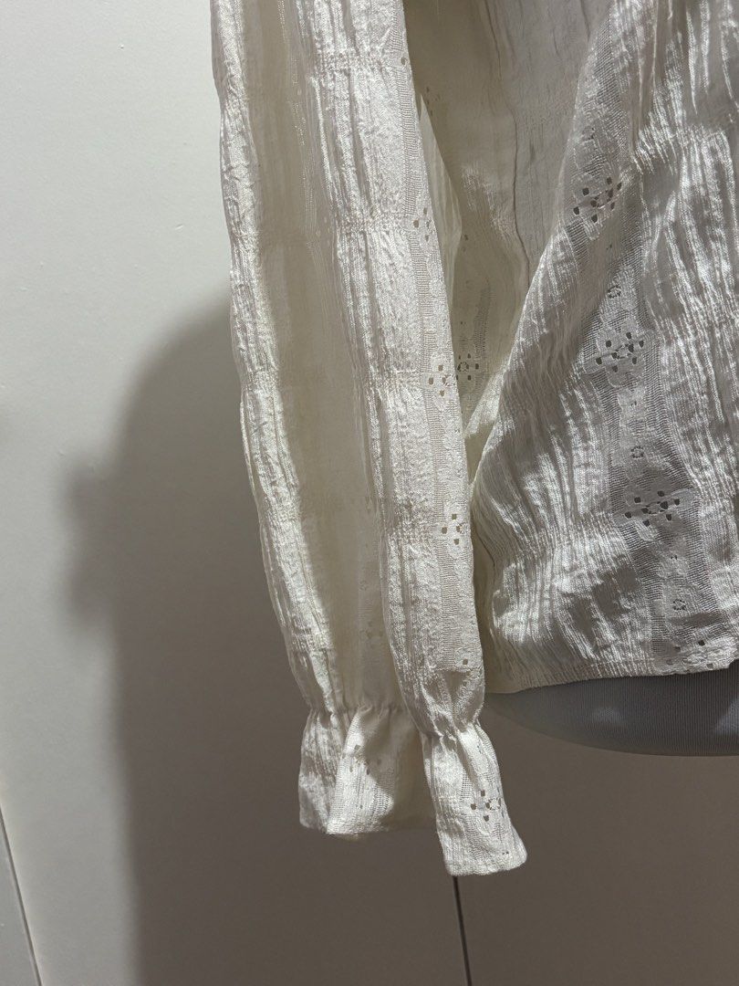 (m-l) White Lace Ruffle Long Sleeve Blouse (Category: Blouses) located in Paranaque City. Submitted by prelovedtinez (Listing ID 1448042393, Image 3). Description: - Cream white blouse with intricate lace details - Features ruffles along the neckline and sleeves - Button-up front with pearl-like buttons - Textured fabric with eyelet details - Long sleeves with ruffled cuffs - Delicate and vintage-inspired design.