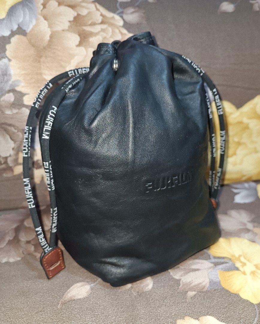 Preloved Fujifilm Leather Drawstring Pouch Bag (Category: Camera Bags & Carriers) located in Pasig City. Submitted by bcthriftedzoneonlineshop (Listing ID 1447994605, Image 1). Description: - Genuine Fujifilm black leather drawstring pouch. - Features embossed Fujifilm logo on the front. - Includes small interior pockets for organization. - Drawstring is branded with Fujifilm lettering. - Ideal for protecting camera lenses, filters, or other smal