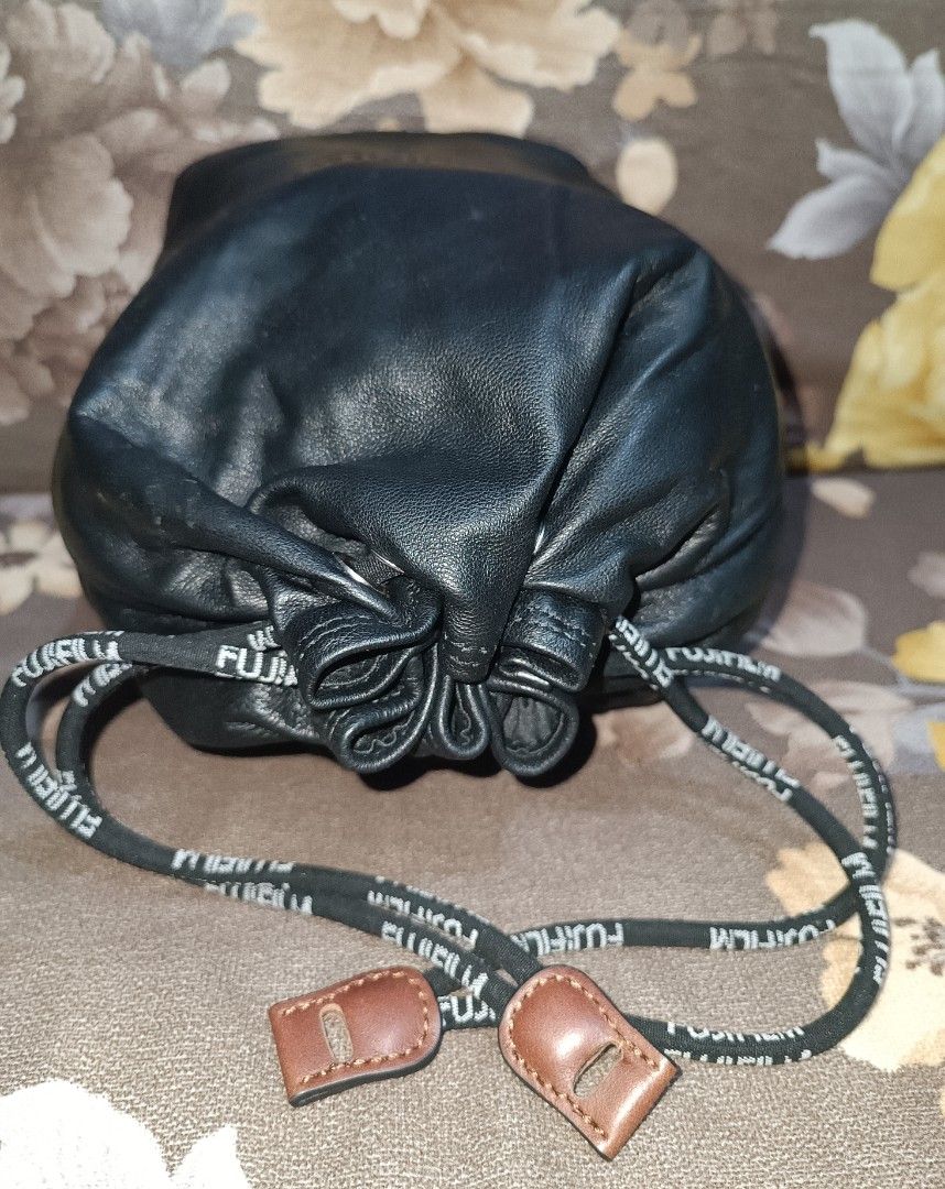 Preloved Fujifilm Leather Drawstring Pouch Bag (Category: Camera Bags & Carriers) located in Pasig City. Submitted by bcthriftedzoneonlineshop (Listing ID 1447994605, Image 3). Description: - Genuine Fujifilm black leather drawstring pouch. - Features embossed Fujifilm logo on the front. - Includes small interior pockets for organization. - Drawstring is branded with Fujifilm lettering. - Ideal for protecting camera lenses, filters, or other smal