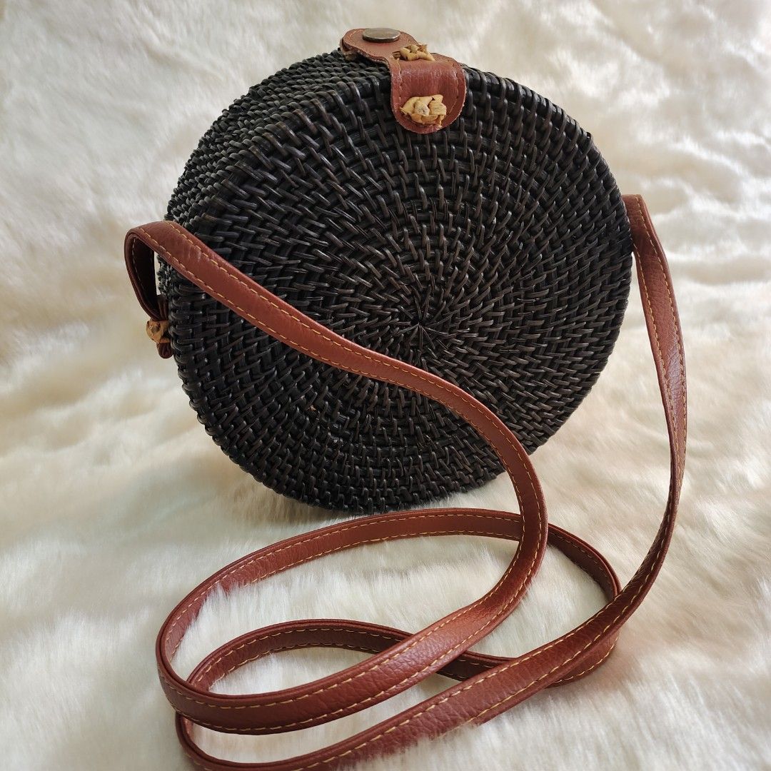 Round Rattan Bag with Leather Strap (Category: Cross-body Bags) located in Binan City. Submitted by apparelsbyeve (Listing ID 1447962702, Image 1). Description: - Round rattan native bag - Dark brown woven material - Brown leather strap and closure details - Lined interior - Fits a phone (shown for size reference - iphone 15 pro) - Ideal for beach trips or casual outings.