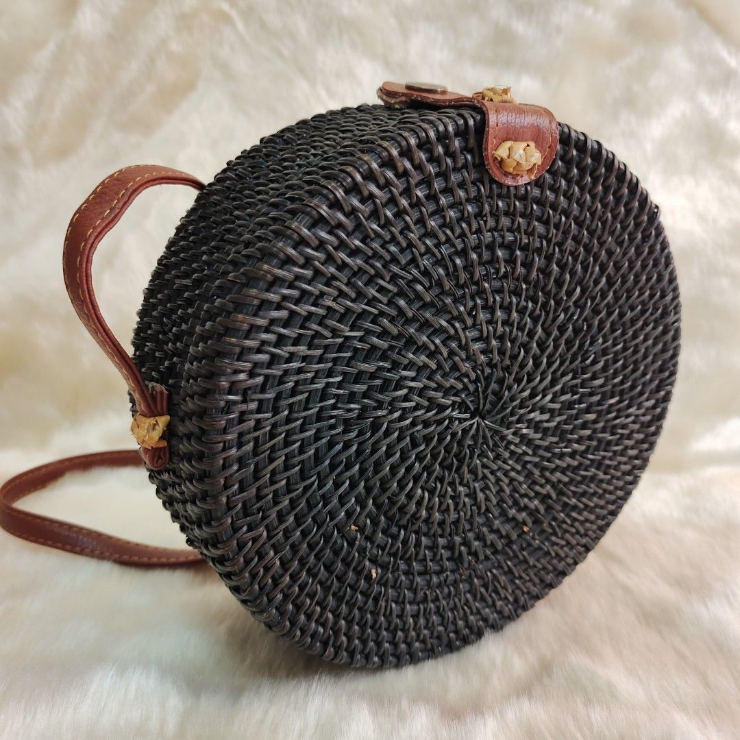 Round Rattan Bag with Leather Strap (Category: Cross-body Bags) located in Binan City. Submitted by apparelsbyeve (Listing ID 1447962702, Image 3). Description: - Round rattan native bag - Dark brown woven material - Brown leather strap and closure details - Lined interior - Fits a phone (shown for size reference - iphone 15 pro) - Ideal for beach trips or casual outings.