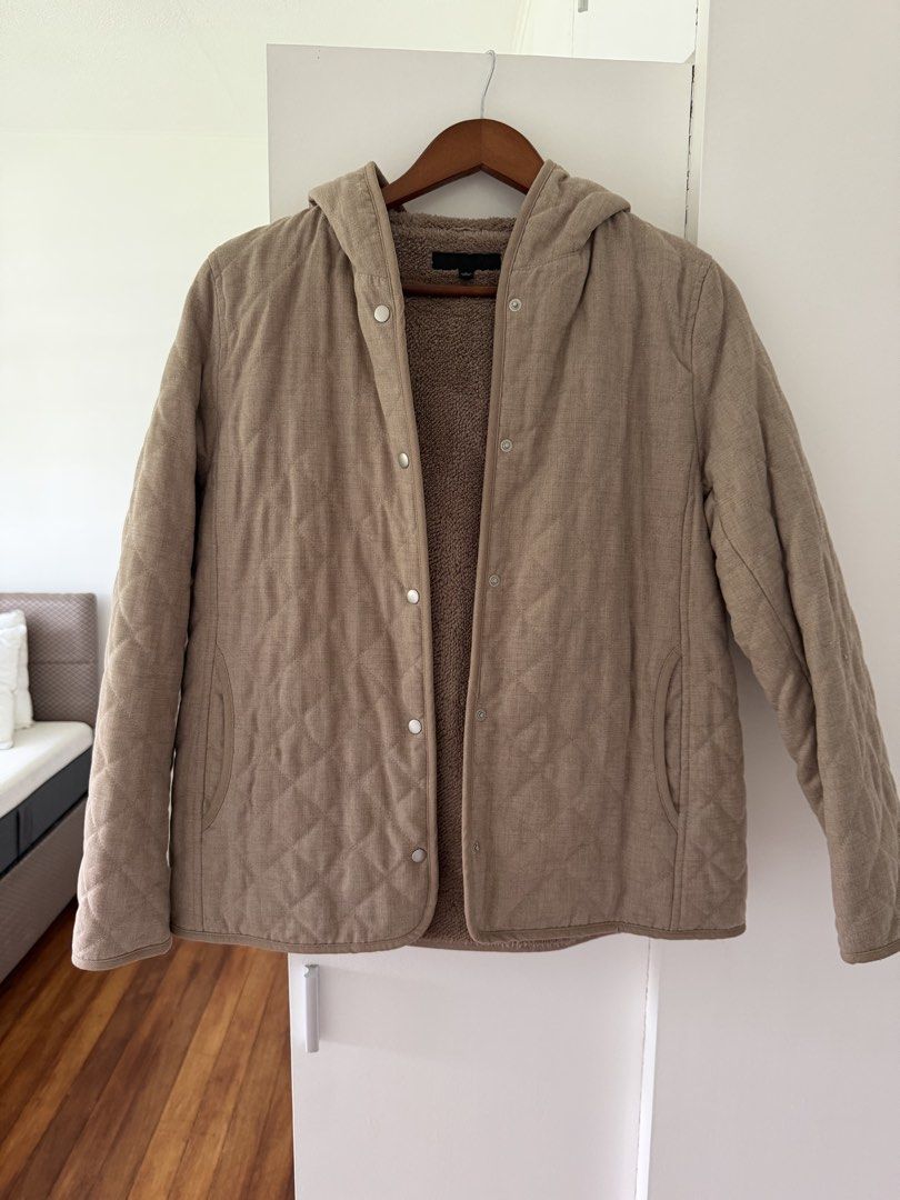 Uniqlo Quilted Hooded Jacket with Lining (Category: Coats, Jackets and Outerwear) located in Taguig. Submitted by onein.oneout_declutter (Listing ID 1447895483, Image 1). Description: - Cozy quilted jacket - Warm sherpa lining - Features a hood - Button-up front - Neutral beige color - Great for layering - Perfect for cooler weather.