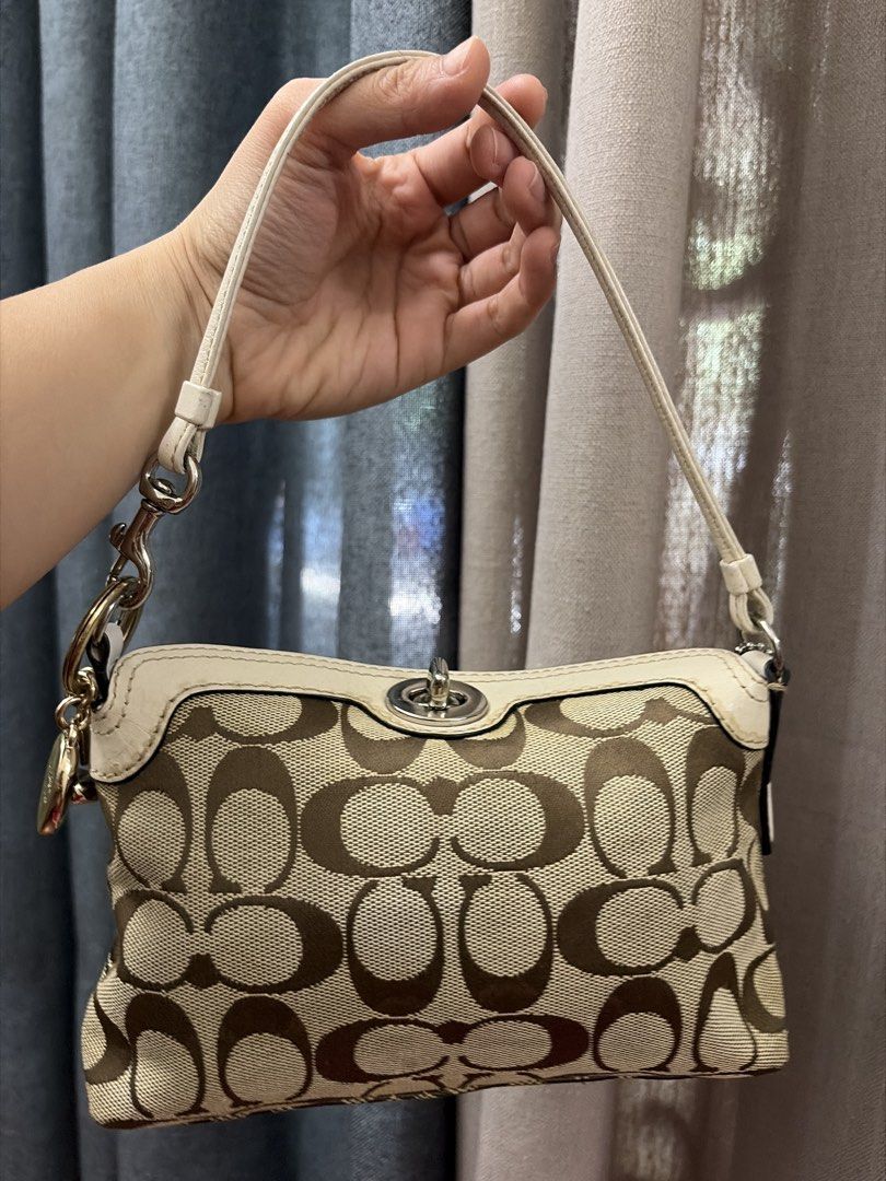 Vintage Coach Turn Lock (Category: Luxury Bags & Wallets) located in Lubao. Submitted by luckygurlsyndrome (Listing ID 1447927462, Image 3). Description: - Classic Coach monogram shoulder bag - Beige and brown canvas with white leather trim - Silver hardware and clasp closure - Small and compact, ideal for essentials - Adjustable strap with clip - Stylish accessory for any outfit - Please check photos for detailed condition Super good condition.
