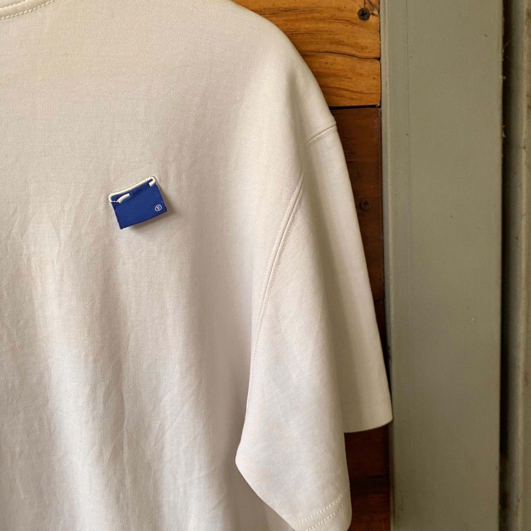 White T-shirt with Graphic Print (Category: Shirts) located in Caloocan City. Submitted by thrivo.co (Listing ID 1447975192, Image 3). Description: - Classic white t-shirt with a stylish graphic print on the front. - Features a unique small blue tag detail on the chest. - Made from soft and comfortable fabric for all-day wear. - Ideal for casual outfits and everyday styling. - Size: Medium (M) -21x25.