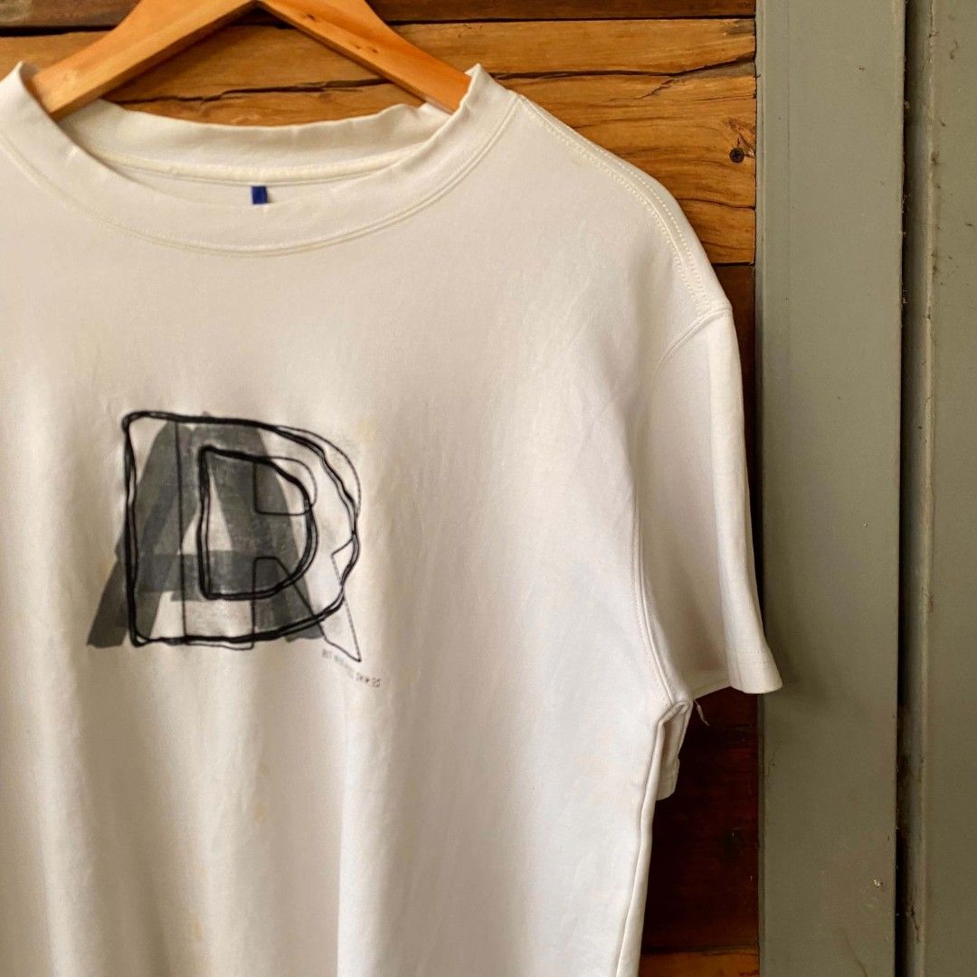 White T-shirt with Graphic Print (Category: Shirts) located in Caloocan City. Submitted by thrivo.co (Listing ID 1447975192, Image 2). Description: - Classic white t-shirt with a stylish graphic print on the front. - Features a unique small blue tag detail on the chest. - Made from soft and comfortable fabric for all-day wear. - Ideal for casual outfits and everyday styling. - Size: Medium (M) -21x25.