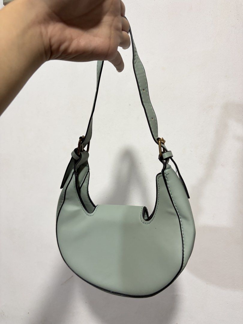 Light Green Crescent Shoulder Bag with Gold Clasp (Category: Shoulder Bags) located in Valenzuela. Submitted by cheaper_finds (Listing ID 1448233039, Image 2). Description: - Trendy light green crescent shoulder bag - Features a chic gold-tone clasp closure - Adjustable strap with buckle for a custom fit - Interior snap closure for added security - Versatile for everyday wear or evening outings.