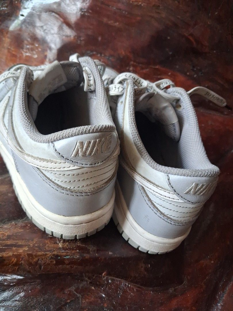 Nike Dunk Low Grey White Sneakers (Category: Sneakers) located in Manila. Submitted by beardedbot (Listing ID 1448105702, Image 2). Description: - Nike Dunks (Grey/White) - Size: 8.5Y - Condition: Used, with some scuffs on soles and minor wear on uppers. - Features: Laces with text detail. - Note: Still has a lot of life left, sold as is..