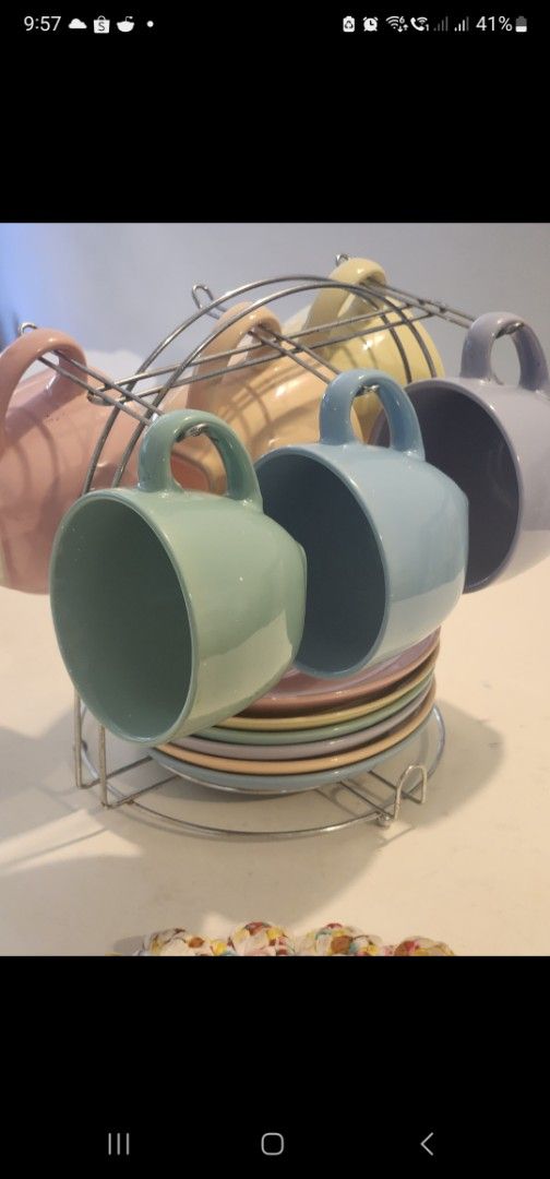 Pastel Ceramic Mugs and Saucers with Rack (Category: Coffee & Tea Tableware) located in Manila. Submitted by babygirl.luxxe (Listing ID 1448089022, Image 2). Description: - Adorable set of pastel mugs and saucers. - Comes with a convenient metal rack for storage. - Features a vibrant color palette: pink, yellow, light blue, teal, and purple. - Ideal for enjoying your favorite coffee or tea. - Adds a charming pop of color to your kitchen space..