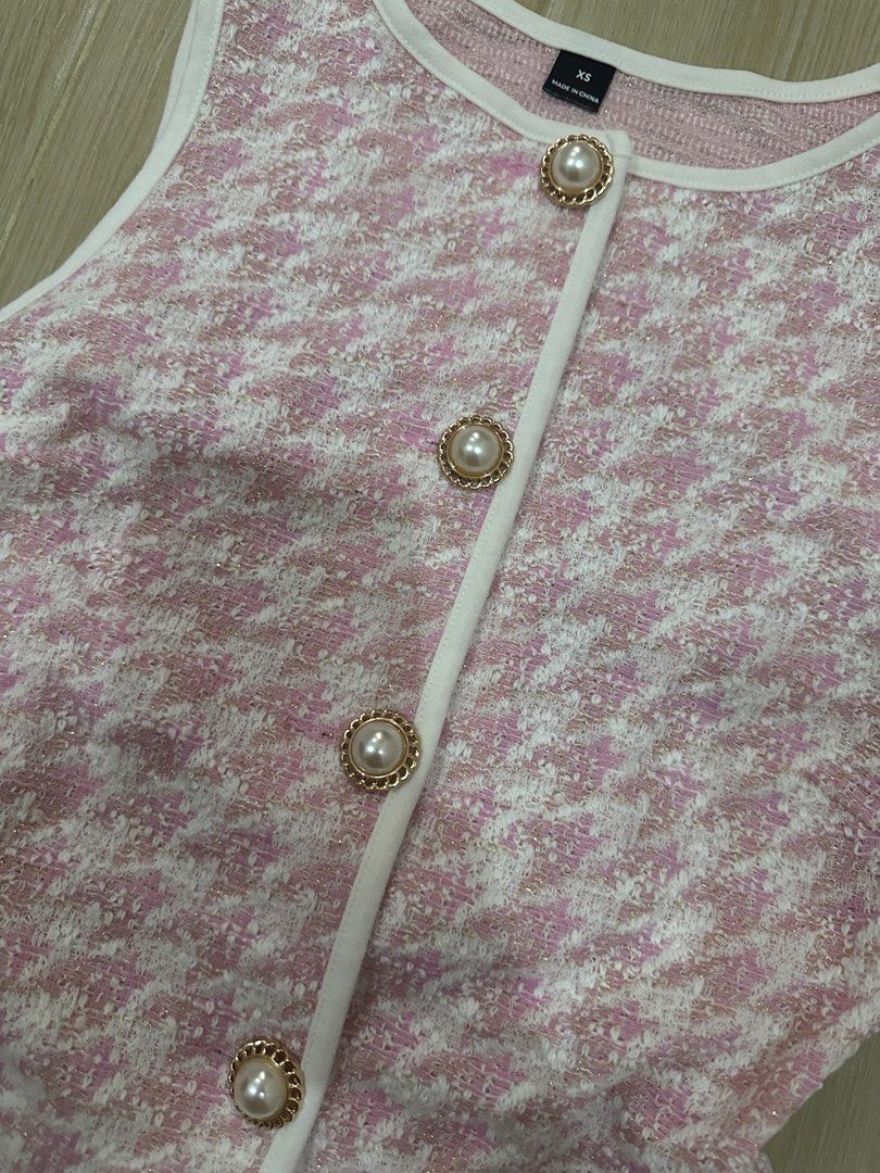 Pink Houndstooth Button-Up Sleeveless Vest (Category: Sleeveless) located in Antipolo. Submitted by waco1313 (Listing ID 1448179802, Image 3). Description: - Adorable pink houndstooth pattern - Sleeveless vest design - Button-up front with pearl-like buttons and gold trim - White piping detail along edges - Adjustable tie at the back for a custom fit - Versatile for layering or standalone wear.