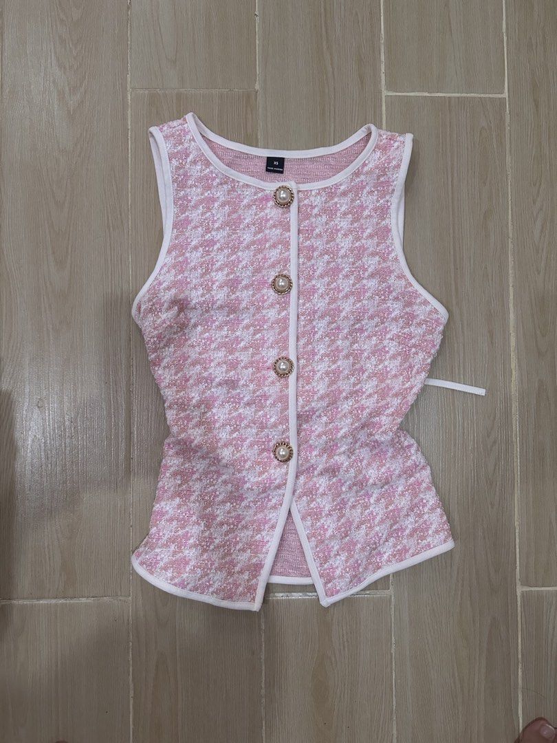 Pink Houndstooth Button-Up Sleeveless Vest (Category: Sleeveless) located in Antipolo. Submitted by waco1313 (Listing ID 1448179802, Image 2). Description: - Adorable pink houndstooth pattern - Sleeveless vest design - Button-up front with pearl-like buttons and gold trim - White piping detail along edges - Adjustable tie at the back for a custom fit - Versatile for layering or standalone wear.