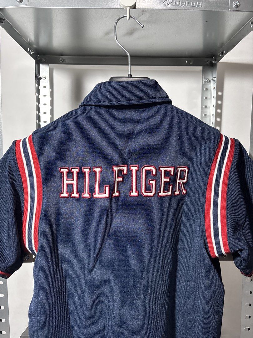 Tommy Hilfiger Short Sleeve Polo (Category: Activewear) located in Santa Rosa. Submitted by popeye00 (Listing ID 1448086486, Image 3). Description: - Navy blue short sleeve polo shirt from Tommy Jeans. - Medium, 24L 18W - Features iconic 'H' logo on the chest. - 'HILFIGER' branding across the back. - Sporty red and white stripe details on the sleeves..