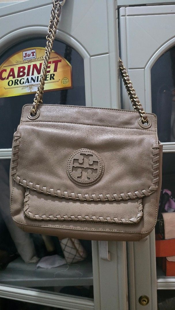 Tory Burch Metallic Shoulder Bag with Chain Strap (Category: Luxury Bags & Wallets) located in Solsona. Submitted by gefferlynne3089 (Listing ID 1448244789, Image 1). Description: - Tory Burch metallic shoulder bag - Features a chain strap - Signature Tory Burch logo on the front flap - Detailed stitching - Ideal for carrying essentials.