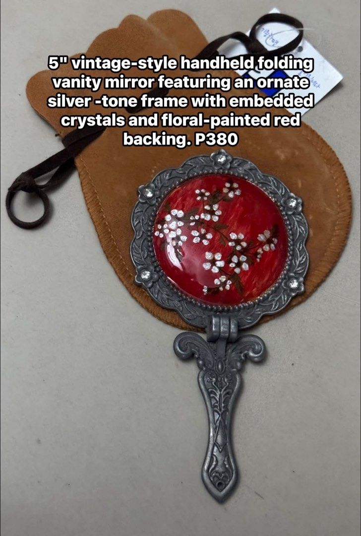 Vintage Folding Vanity Mirror - Ornate Silver Tone Frame (Category: Mirrors) located in Mandaluyong City. Submitted by elainelawenko (Listing ID 1448186970, Image 1). Description: - 5" handheld folding vanity mirror - Vintage style with ornate silver-tone frame - Red backing with floral painted design and embedded crystals - Includes a brown pouch - Ideal for travel or display.