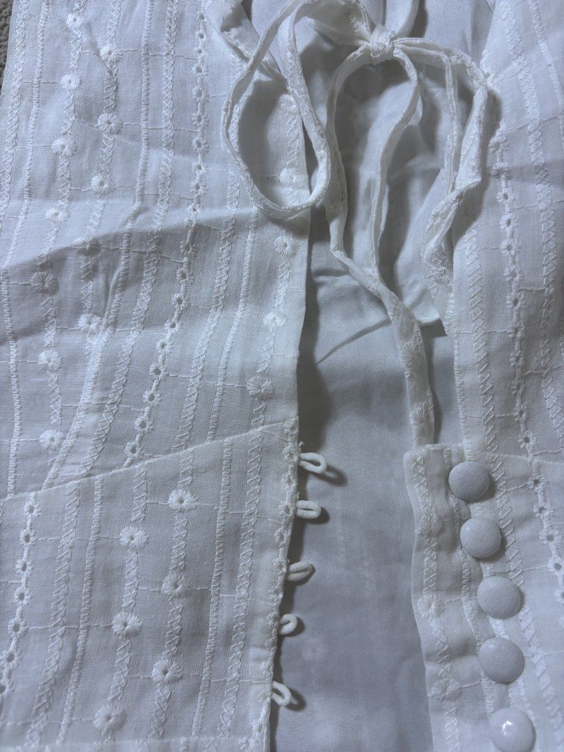 White Broderie Anglaise Vest with Tie Front (Category: Sleeveless) located in Makati City. Submitted by skelssei (Listing ID 1448165692, Image 3). Description: - White sleeveless vest - Features delicate broderie anglaise with floral patterns - Vertical stripe detailing - Tie front closure with button details down the front - Classic collar neckline - Estimated size: Small to Medium - Ideal for stylish layering.
