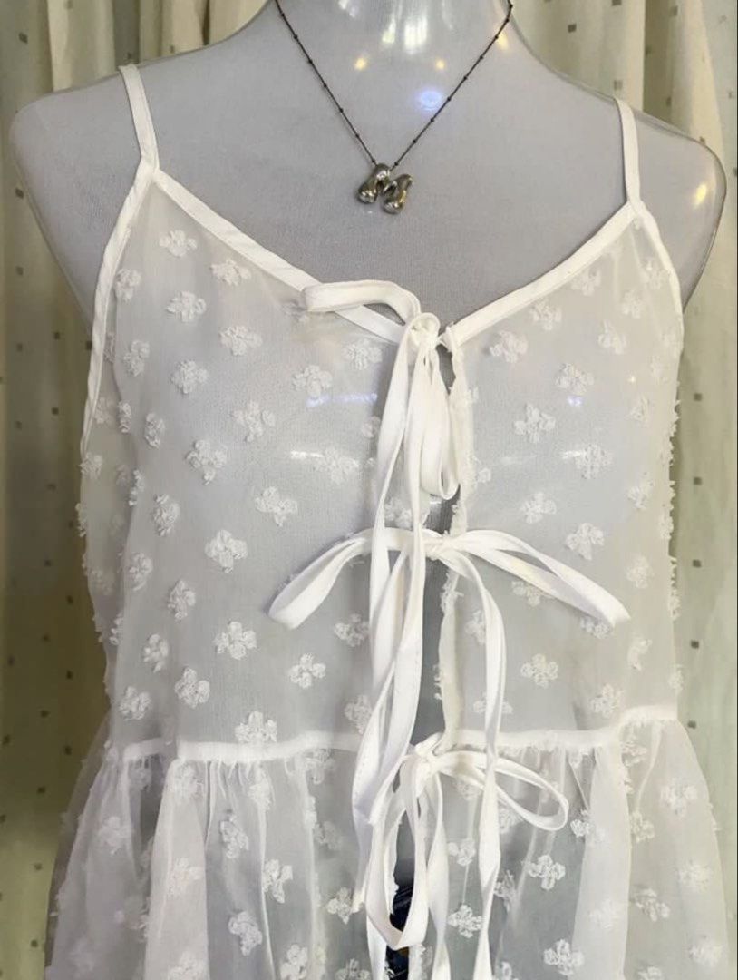 White Sheer Tie-Front Babydoll Top (Category: Blouses) located in Manila. Submitted by cami0110 (Listing ID 1448175139, Image 3). Description: - White sheer babydoll top - Textured floral pattern all over - Ribbon ties at the front - Thin spaghetti straps - Flowy, babydoll silhouette - Ideal for layering or as a beach cover-up.