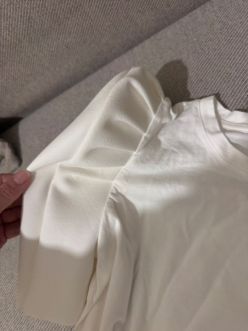 ZARA White T-shirt with Statement Puffy Sleeves (Category: Shirts) located in Mandaluyong City. Submitted by cartmyitems (Listing ID 1448190908, Image 3). Description: - Brand: ZARA - Color: White - Style: T-shirt with unique structured puffy sleeves - Sleeve Texture: Smooth, almost leather-like - Body Material: Soft cotton - Size: S - Key Feature: Statement piece to elevate casual outfits.