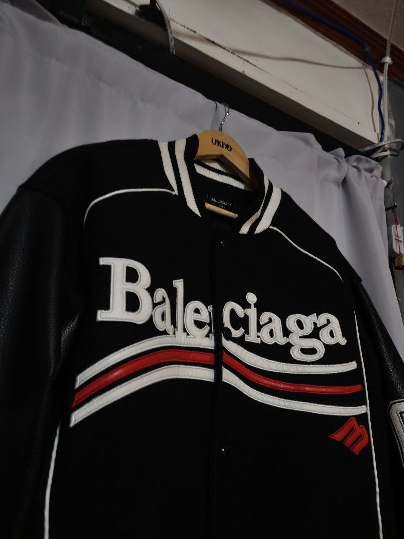 Balenciaga Varsity Bomber Jacket Black Leather (Category: Coats, Jackets and Outerwear) located in Aloran. Submitted by ukiyo_goods (Listing ID 1448411794, Image 3). Description: - Authentic Balenciaga Varsity Bomber Jacket - Color: Black with White and Red Accents - Features iconic Balenciaga logo across the chest - Premium leather sleeves - Distinctive '19' detail on the sleeve - Unisex design, suitable for all - Ideal for stylish casual wear -