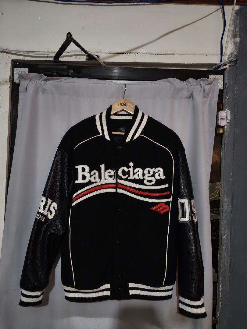 Balenciaga Varsity Bomber Jacket Black Leather (Category: Coats, Jackets and Outerwear) located in Aloran. Submitted by ukiyo_goods (Listing ID 1448411794, Image 1). Description: - Authentic Balenciaga Varsity Bomber Jacket - Color: Black with White and Red Accents - Features iconic Balenciaga logo across the chest - Premium leather sleeves - Distinctive '19' detail on the sleeve - Unisex design, suitable for all - Ideal for stylish casual wear -