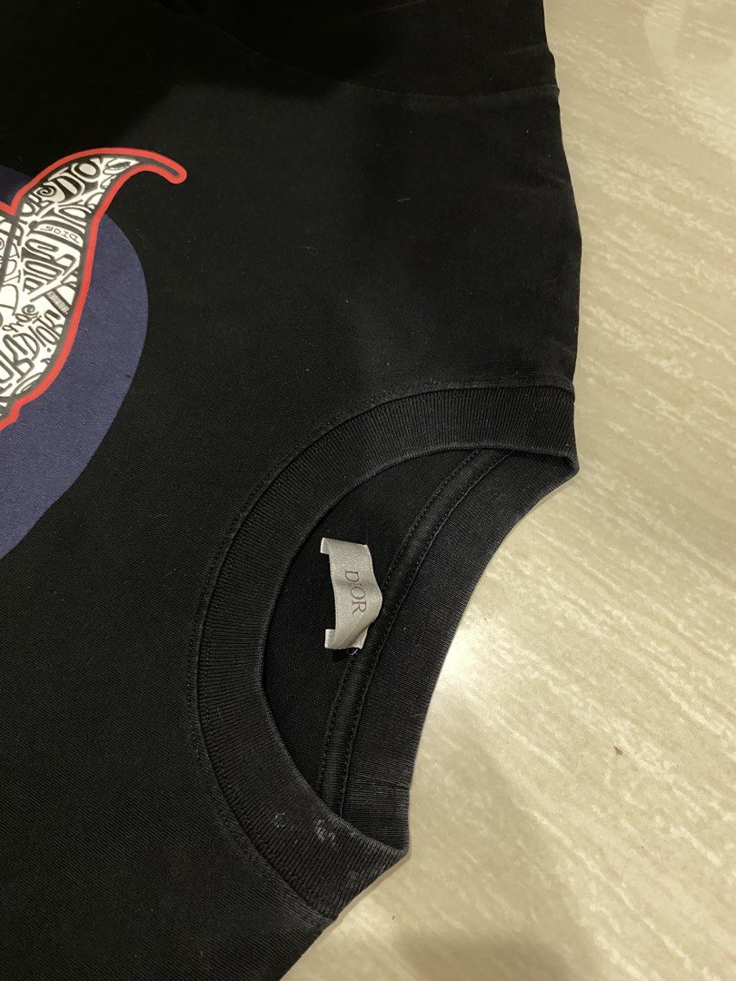 Dior x Stussy T-shirt (Category: Tshirts & Polo Shirts ) located in Luisiana. Submitted by matchacoach (Listing ID 1448389929, Image 2). Description: Black Dior t-shirt. Features a graphic print of a bull's head made of text. Crew neck, short sleeves. Good for casual wear. Check photos for details. ps. The neck area has a small white spot, but it can still be cleaned since it’s just dirt. Message me for more details! Price is negotiable.