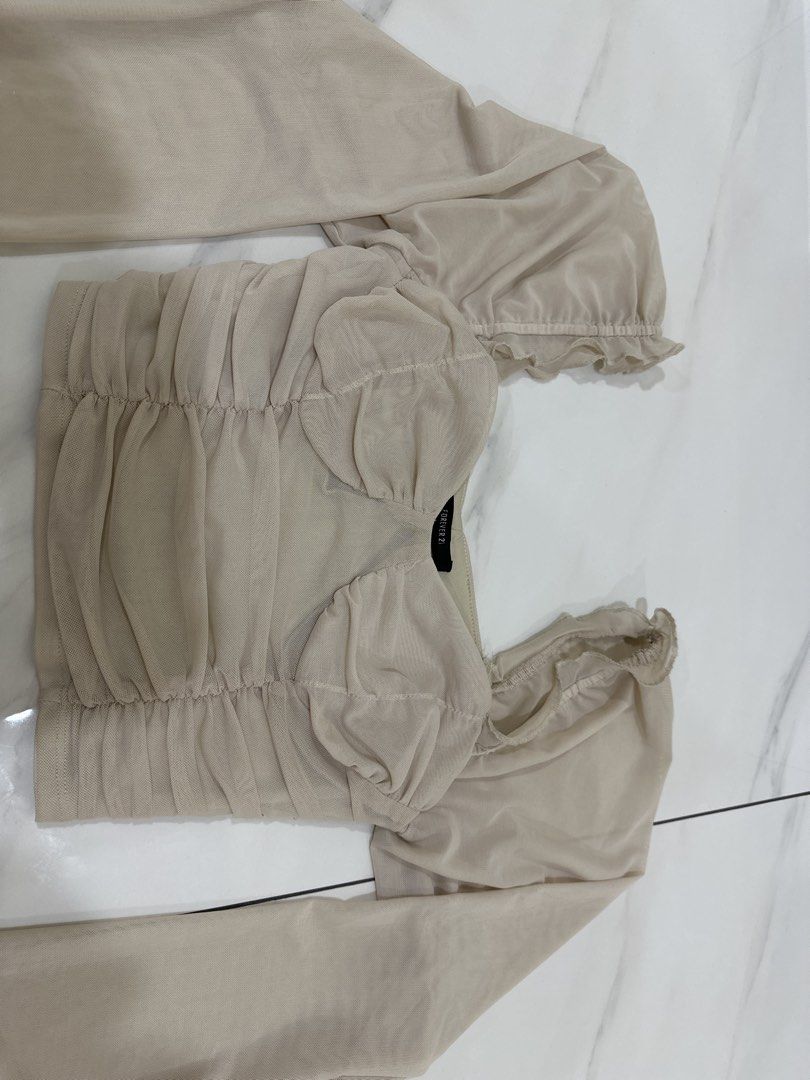 Forever 21 Beige Mesh Ruched Puff Sleeve Top Size S (Category: Blouses) located in Kuala Lumpur. Submitted by princess7766 (Listing ID 1448454914, Image 1). Description: - Beige mesh top from Forever 21 - Ruched detailing on the front - Puff sleeves - Square neckline with ruffled trim - Side zipper closure - Size S - Perfect for dressing up or down.