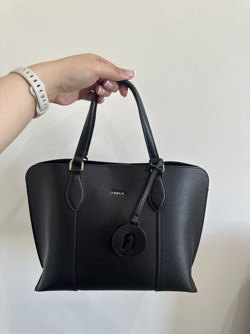 Furla Black Leather Tote Bag (Category: Luxury Bags & Wallets) located in Taguig. Submitted by wildcloud_d77321 (Listing ID 1448277989, Image 1). Description: - Classic black Furla tote bag - Made from textured leather - Features top handles - Detachable Furla logo charm - Spacious interior - Ideal for daily use or work - Comes with original Furla paper bag.