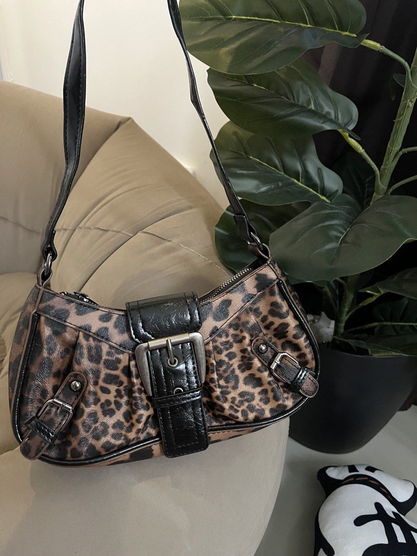Leopard Print Shoulder Bag with Buckle Detail (Category: Shoulder Bags) located in Trece Martires City. Submitted by miaaamic (Listing ID 1448299477, Image 2). Description: - Adorable leopard print shoulder bag - Features a stylish black buckle on the front - Adjustable strap for comfortable wear - Secure zipper closure - Ideal for carrying your daily essentials - Adds a fun and trendy touch to any outfit.