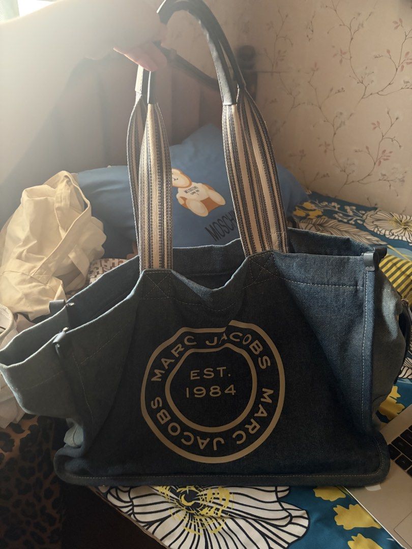 Marc Jacobs Denim Tote Bag Est. 1984 (Category: Luxury Bags & Wallets) located in San Pedro. Submitted by AuthenticBrandedItems (Listing ID 1448374636, Image 2). Description: - Classic Marc Jacobs denim tote bag - Features iconic 'Est. 1984' logo - Spacious interior with zip closure - Comfortable shoulder straps - Durable and stylish denim material - Ideal for everyday use or travel.