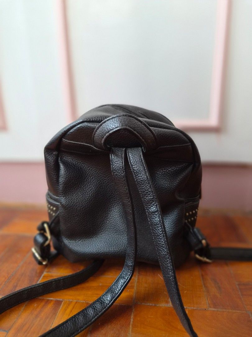 Parisian Black Studded Mini Backpack (Category: Backpacks) located in Santo Tomas. Submitted by anacristin90526 (Listing ID 1448309375, Image 2). Description: - Cute black mini backpack - Features a cool starburst stud design on the front pocket - Zipper closure - Adjustable straps - Small and compact, ideal for carrying essentials - Made of faux leather - Accented with gold hardware details.