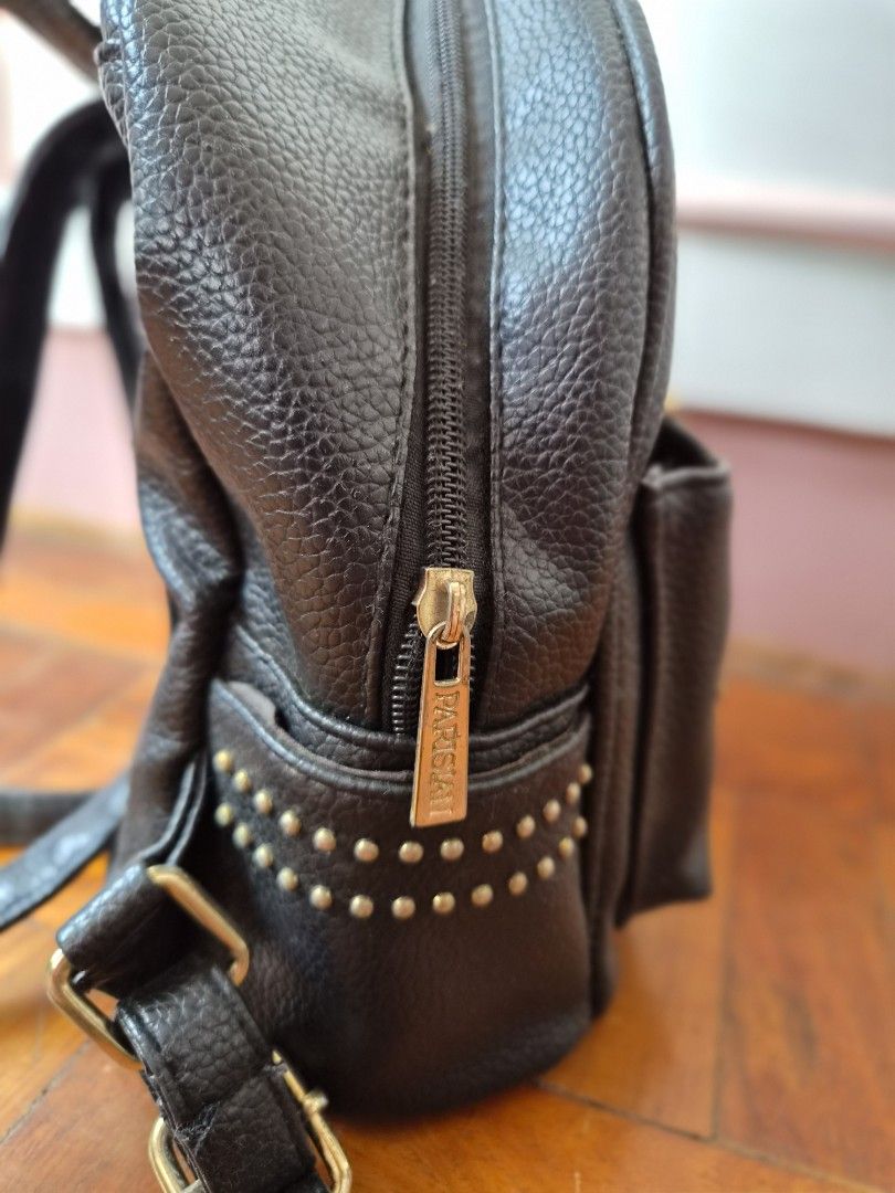 Parisian Black Studded Mini Backpack (Category: Backpacks) located in Santo Tomas. Submitted by anacristin90526 (Listing ID 1448309375, Image 3). Description: - Cute black mini backpack - Features a cool starburst stud design on the front pocket - Zipper closure - Adjustable straps - Small and compact, ideal for carrying essentials - Made of faux leather - Accented with gold hardware details.