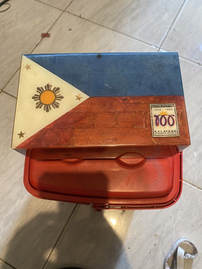 Philippine Centenary 100 Years Kalayaan Storage Box (Category: Storage Boxes & Baskets) located in Marikina City. Submitted by jtv17 (Listing ID 1448344004, Image 1). Description: - Commemorative storage box for Philippine Centenary (1898-1998). - Features Philippine flag design and '100 Kalayaan 1898-1998' inscription. - Interior lined with red fabric. - Ideal for organizing small personal items. - Shows some signs of wear, but fully functional.