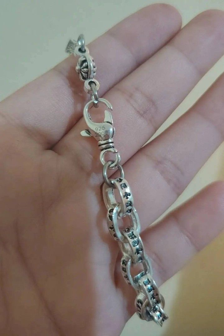 Chrome Heart bracelet (Category: Bracelets) located in Baguio. Submitted by thrifty_cool (Listing ID 1448477994, Image 3). Description: - Cool silver chain bracelet - Features dice and cross charms - Engraved text on links - Secure lobster clasp closure - Stamped 925, indicating sterling silver - Perfect accessory for any outfit.