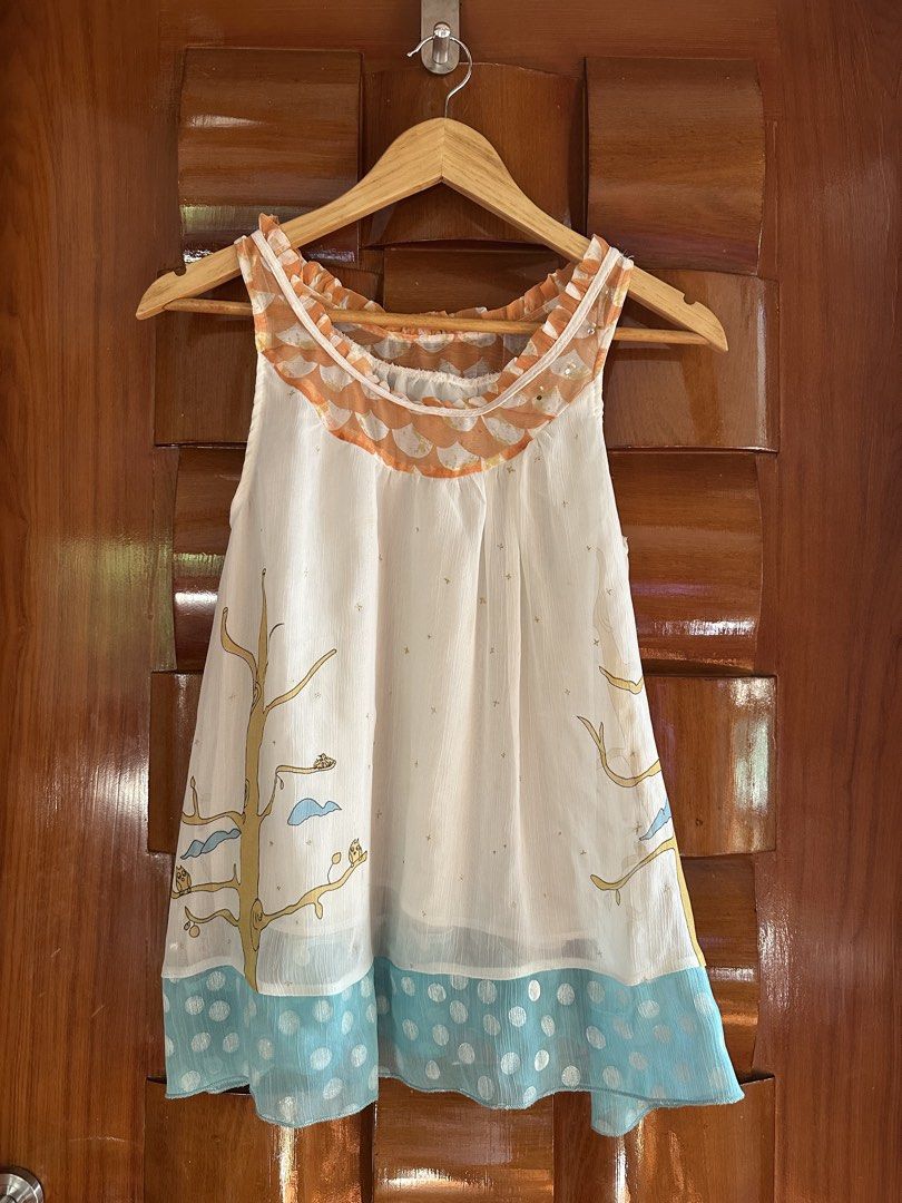 White Sleeveless Top with Tree and Owl Print (Category: Sleeveless) located in Muntinlupa City. Submitted by belica (Listing ID 1448389576, Image 1). Description: - Adorable white sleeveless top - Whimsical print featuring trees, owls, and clouds - Scalloped orange neckline trim with subtle sparkle - Blue polka dot border along the hem - Lightweight fabric, ideal for hot weather - Versatile piece, pairs well with shorts or jeans.