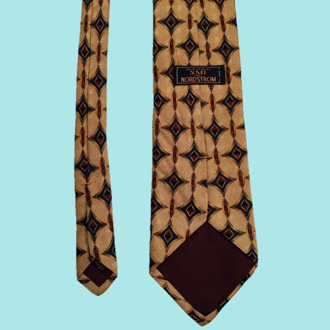 XMI for Nordstrom Silk Tie (Category: Ties) located in Dinalupihan. Submitted by senkustuff (Listing ID 1448373243, Image 3). Description: - Gold tie with a sophisticated geometric pattern. - Features navy blue and burgundy diamond shapes in an oval design. - Hand-sewn quality by XMI for Nordstrom. - An excellent accessory to elevate any formal outfit. - Adds a timeless, classic touch to your ensemble..