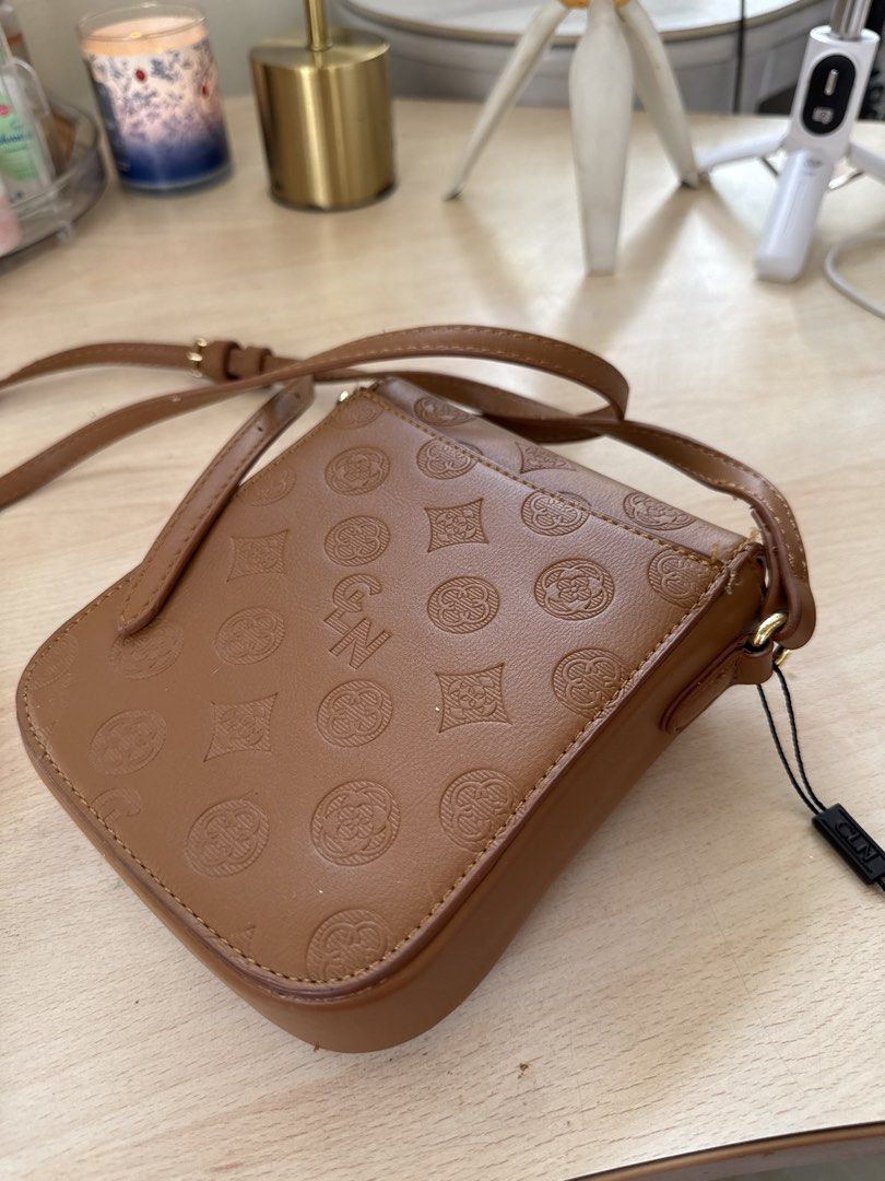 Brown Monogram Crossbody Bag with Gold Clasp (Category: Cross-body Bags) located in Santa Rosa. Submitted by ninjalei (Listing ID 1448552262, Image 2). Description: - Cute brown crossbody bag - All-over monogram pattern - Gold flower clasp - Adjustable strap - Minor scuffing on front clasp area - Ideal for carrying essentials (phone, small wallet) - Perfect everyday size.