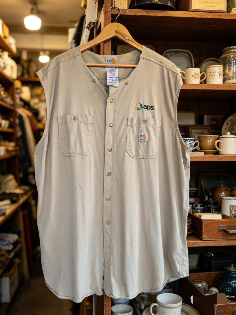 Carhartt FR Flame Resistant Work Shirt APS Uniform (Category: Tshirts & Polo Shirts ) located in Castilla. Submitted by ktrepft (Listing ID 1448516815, Image 1). Description: - Brand: Carhartt 26 by 35 - Color: Tan - Size: X-Large - Style: Sleeveless, Button-up Work Shirt - Pockets: Two chest pockets - Logos: 'APS' embroidered on left chest, 'FR' logo on left sleeve - Material: 100% Cotton - Feature: Flame Resistant (FR).