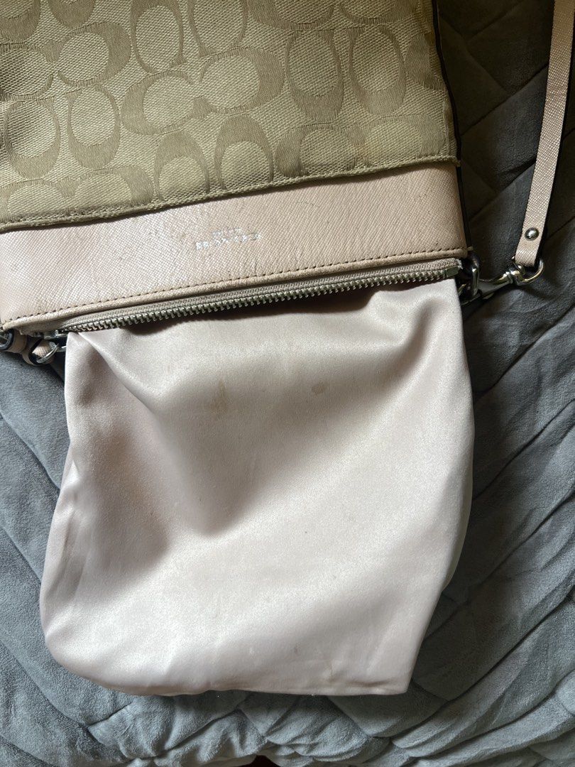 Coach Signature Monogram Crossbody Bag (Category: Luxury Bags & Wallets) located in Saravia. Submitted by clynlyn (Listing ID 1448542953, Image 3). Description: - Authentic Coach crossbody bag - Signature monogram canvas with light pink leather trim and strap - Secure zipper closure - Adjustable strap for comfortable wear - Interior lined in light pink satin-like material - Minor marks present inside the bag.