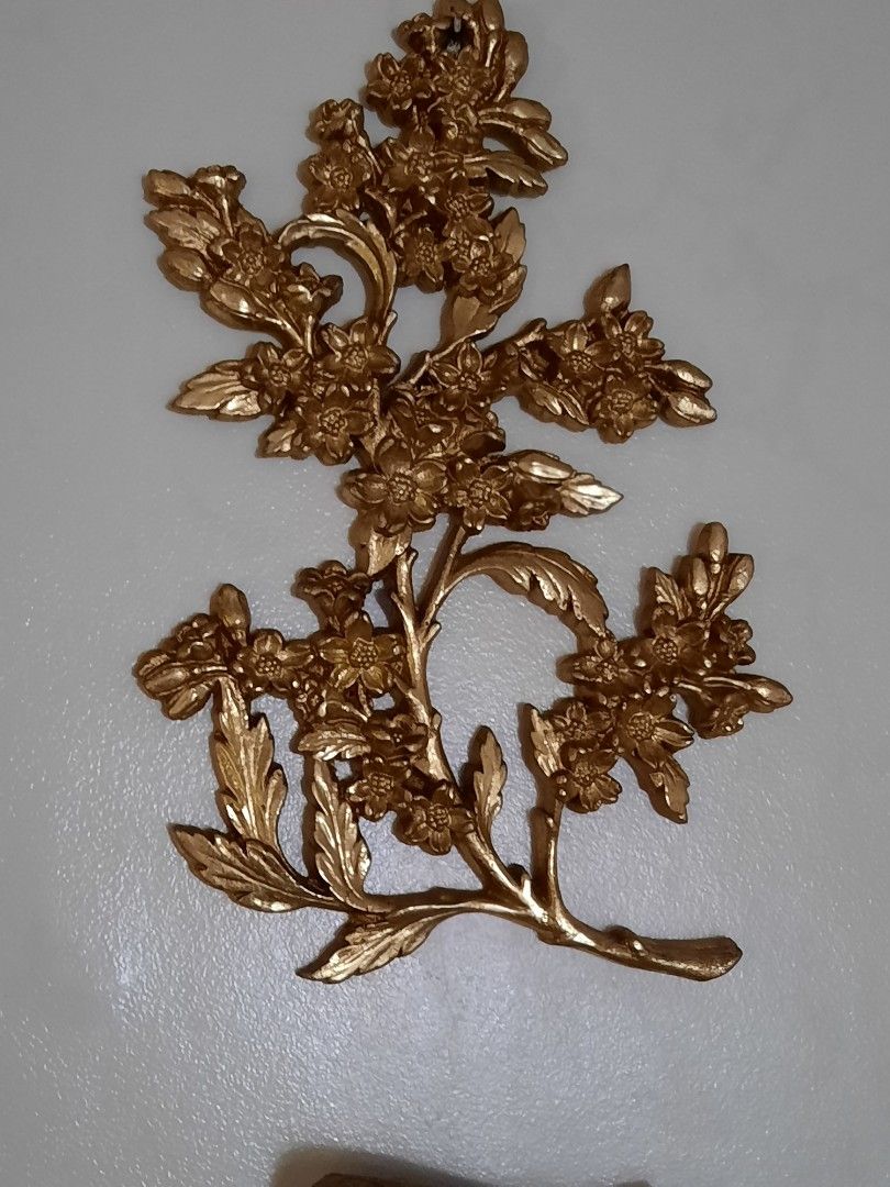 Gold Wall Decor - Floral Branch and Scroll with Hands (Category: Wall Decor) located in Manila. Submitted by epictree.a37e8d (Listing ID 1448642365, Image 1). Description: - Set of two elegant gold-colored wall decor pieces. - Piece 1: Delicate floral branch with numerous small flowers and leaves. - Piece 2: Classical scroll design featuring musical notes, a rolled edge, hands holding a staff, and a laurel wreath. - Ideal for creating a vintage o