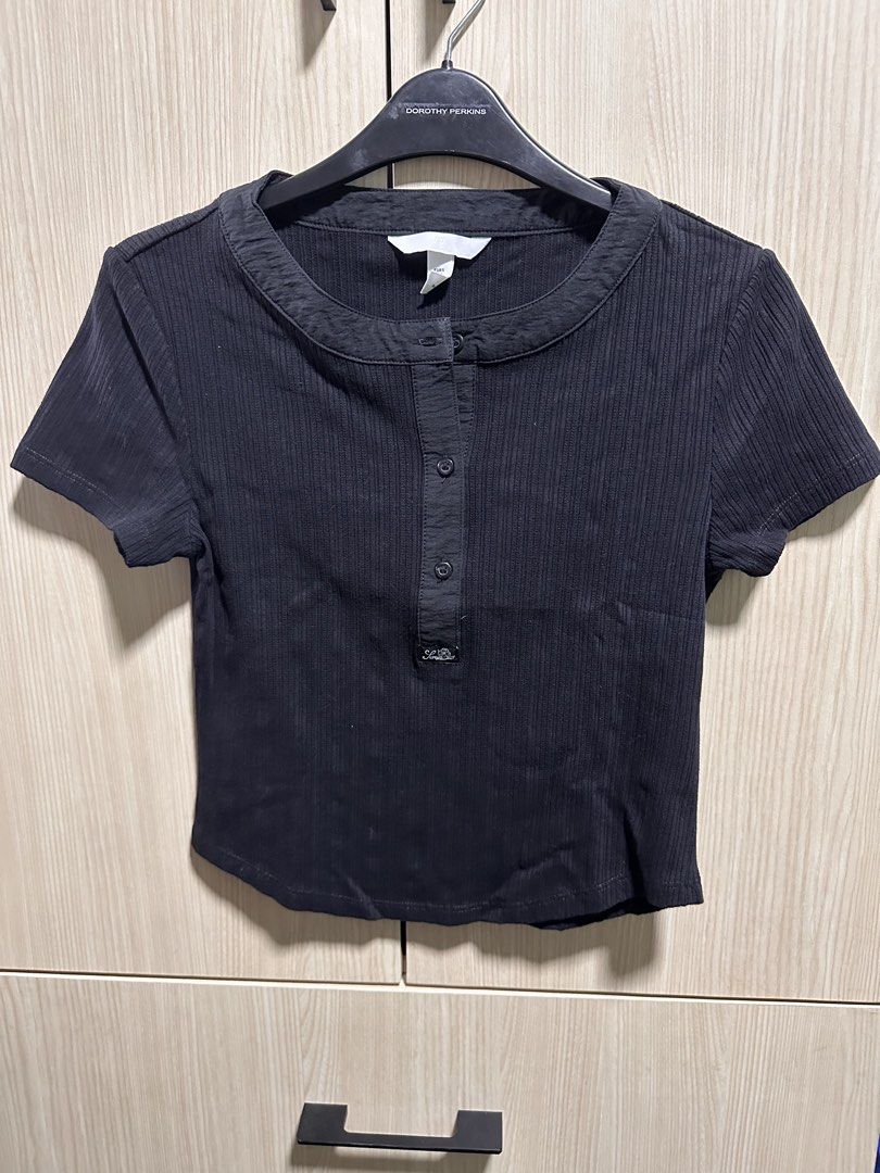 H&M Black Ribbed Cropped Henley Top (Category: Shirts) located in Makati City. Submitted by rmgcloset (Listing ID 1448491718, Image 1). Description: - Black H&M cropped top - Ribbed material - Short sleeves - Henley neckline with button details - Estimated size: S - Ideal for casual wear.